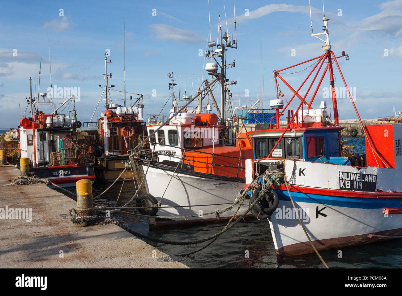 colourful and multicoloured fishing boats moored at the quayside on a sunny day in Kalk Bay harbour or harbor, False Bay, Cape Peninsula, South Africa Stock Photo