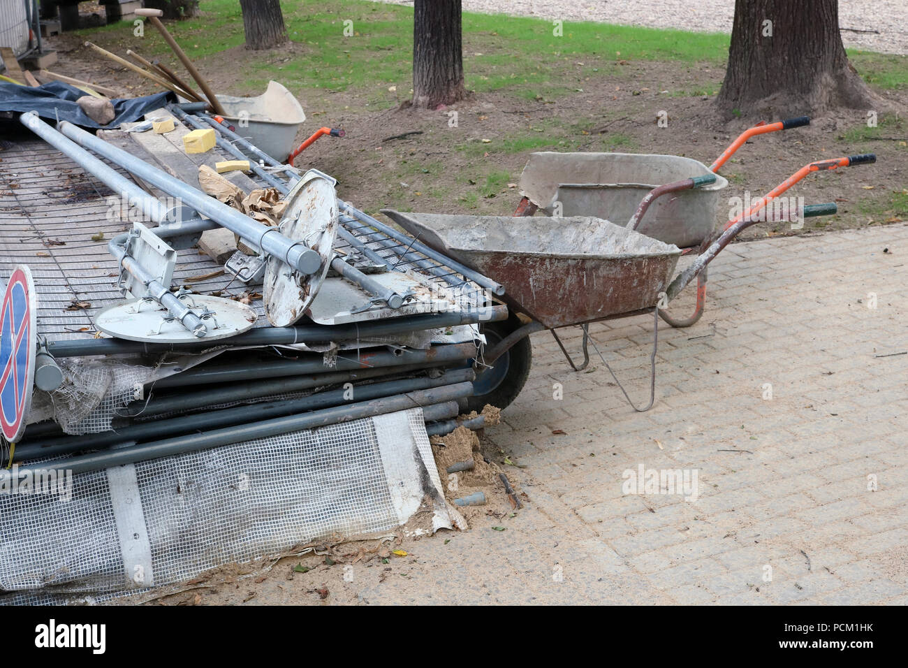 Landfill of road construction equipment in the city public park - mesh fence, wheelbarrow, signs and so on. Stock Photo