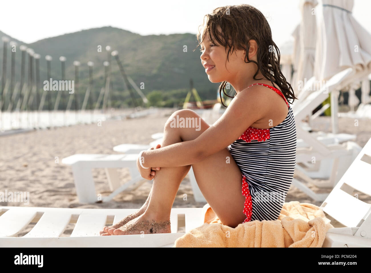 little girl sitting on a deck chair at the beach Stock Photo Alamy