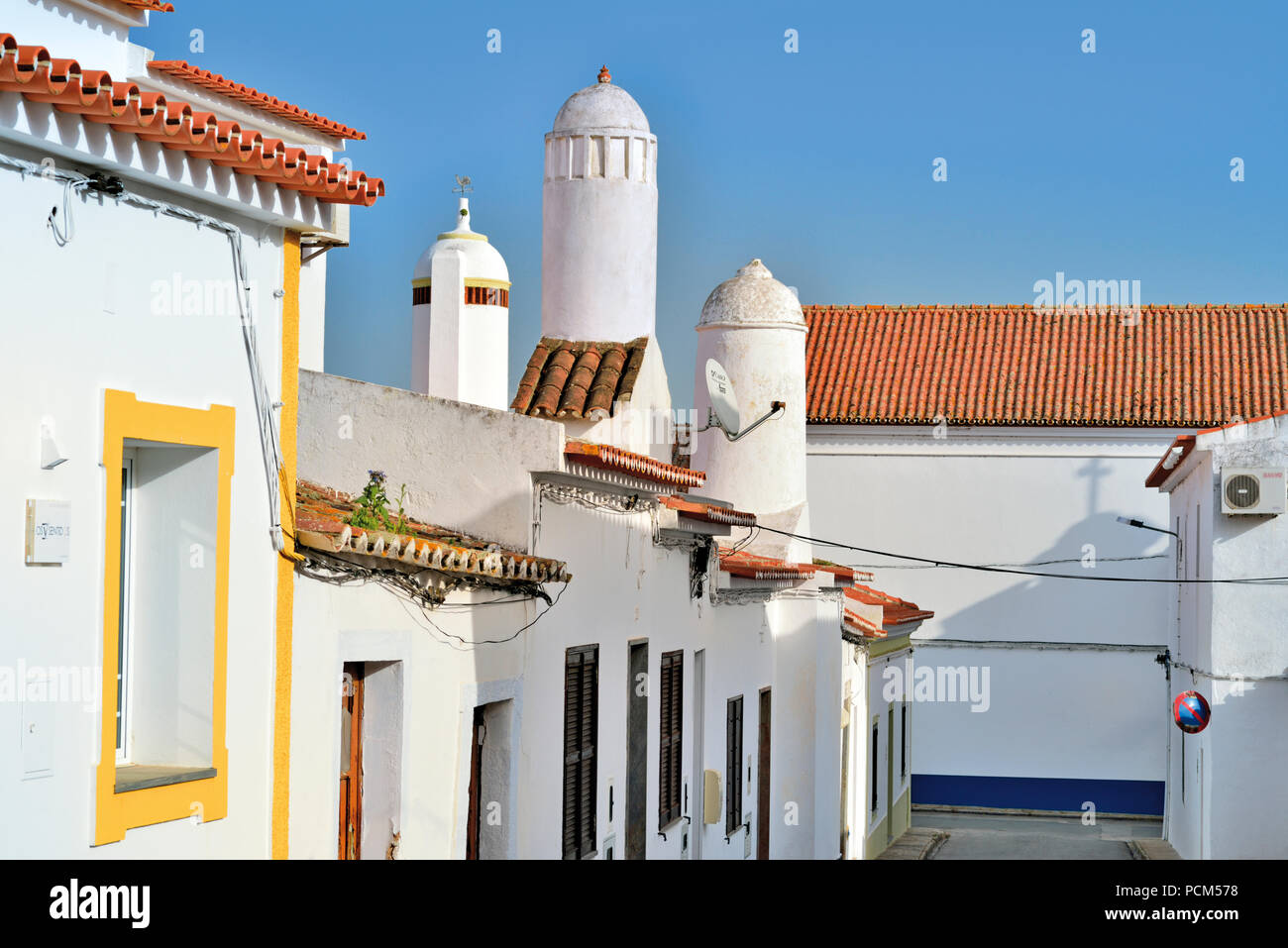 White washed houses and huge chimneys in an idyllic side alley Stock Photo