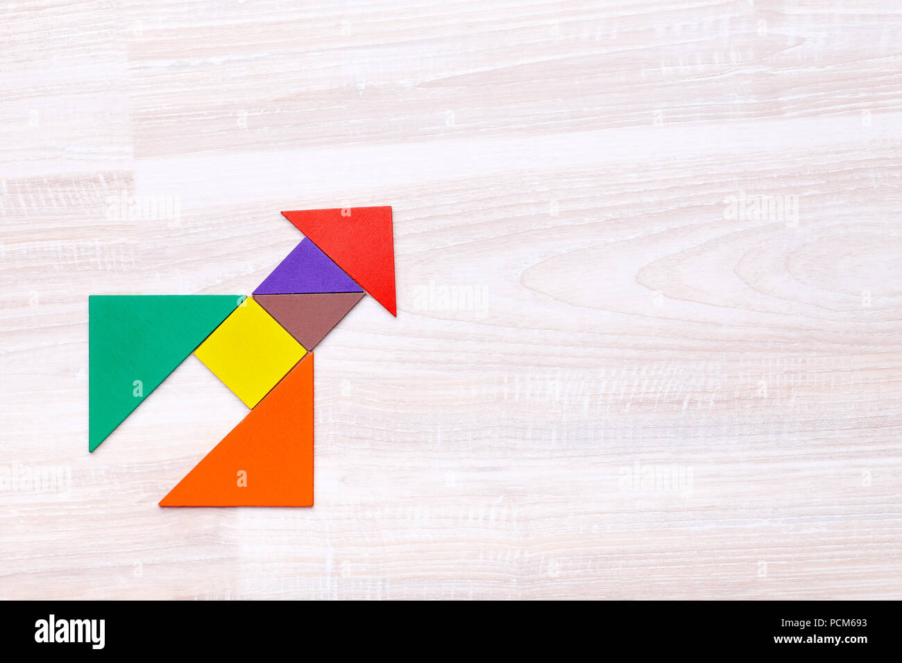 From above tangram figures into shape of rocket on wooden table with copy space Stock Photo