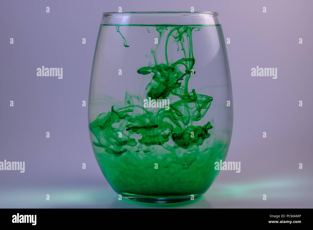 Swirls of food coloring in a glass of water. Stock Photo