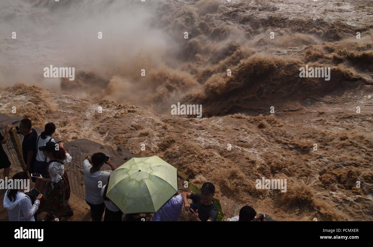 Linfen, China's Shanxi Province. 3rd Aug, 2018. Tourists view Hukou Waterfall of the Yellow River in Linfen, north China's Shanxi Province, Aug. 3, 2018. Due to heavy rainfall at the upper reaches of the Yellow River, the water volume of Hukou Waterfall surges. Credit: Lyu Guiming/Xinhua/Alamy Live News Stock Photo