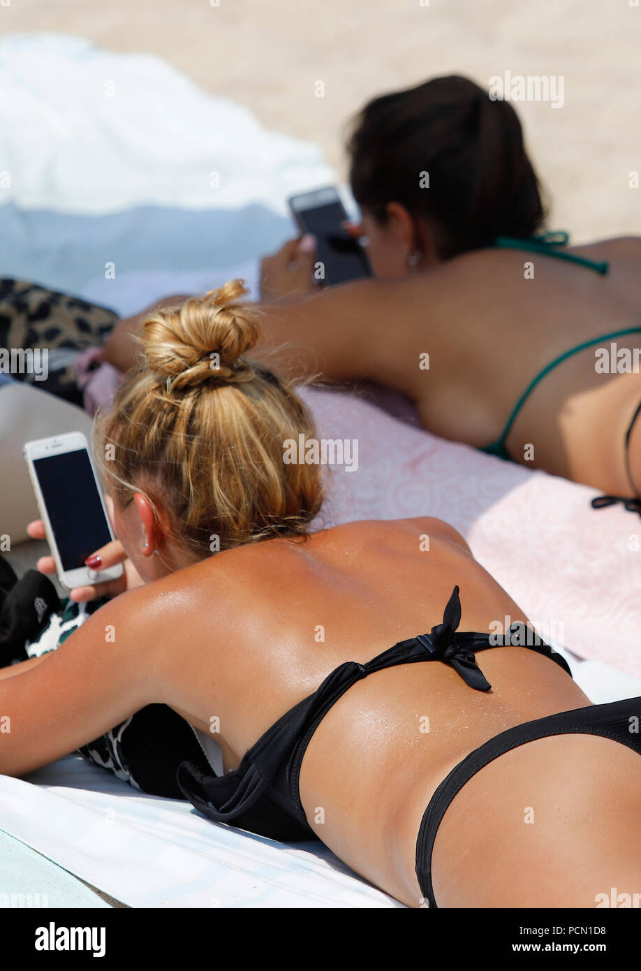 Palma de Mallorca, Spain. 03rd Aug, 2018. Women use their smartphone while  sunbathing on the beach of El Arenal, one of the main destinations for  German and Dutch tourists during the summer
