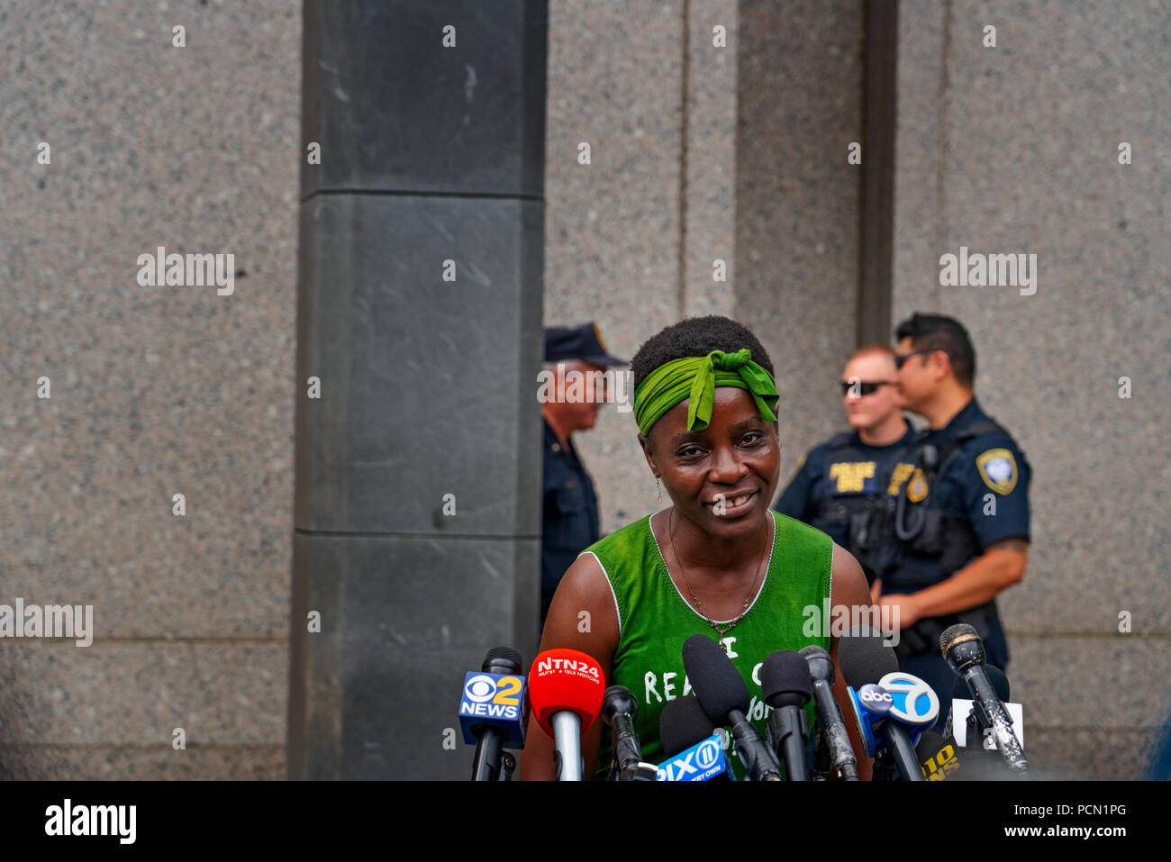 New York, New York, U.S., 3 August 2018  Immigration activist Therese Patricia Okoumou speaks outside federal court in Manhattan after hearing on trespassing & disorderly conduct charges.  Okoumou, a native of Congo, scaled the base of the Statue of Liberty on July 4, 2018, to protest against Trump administration immigration policies.  Okoumou wore a green dress to court bearing the words “I really care why won’t u?” – a response to first lady Melania Trump, who wore a jacket with the words “I really don’t care, do u?” when she visited a facility for migrant children in June. Stock Photo