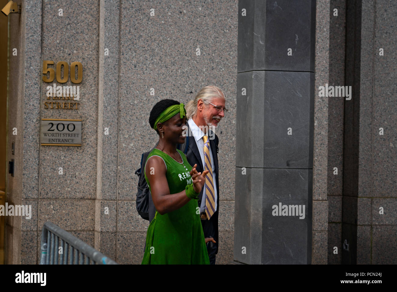 New York, New York, U.S., 3 August 2018 Immigration activist Therese Patricia Okoumou, with lawyer Ron Kuby, walks out of federal court in Manhattan after a hearing on trespassing and disorderly conduct charges.  Okoumou scaled the base of the Statue of Liberty on July 4, 2018, to protest against Trump administration immigration policies.  Okoumou wore a green dress to court bearing the words “I really care why won’t u?” – a response to first lady Melania Trump, who wore a jacket with the words “I really don’t care, do u?” when she visited a facility for migrant children in June. Stock Photo