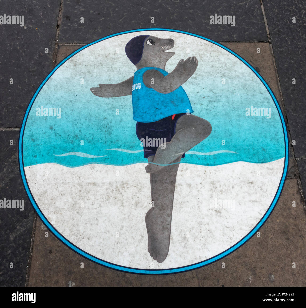 Glasgow, Scotland. 04th August 2013. Bonnie the Seal, Mascot of the Glasgow 2018 European Championships, demonstrating one of the Championship sports, Synchronised swimming, on a decal on a city centre pavement. The European Championships run from 02 August until 12 August 2018. Credit: Elizabeth Leyden/Alamy Live News Stock Photo