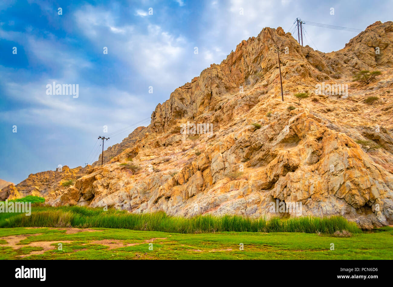 Beautiful yellow hills, green meadow and blue sky from Muscat, Oman. Stock Photo