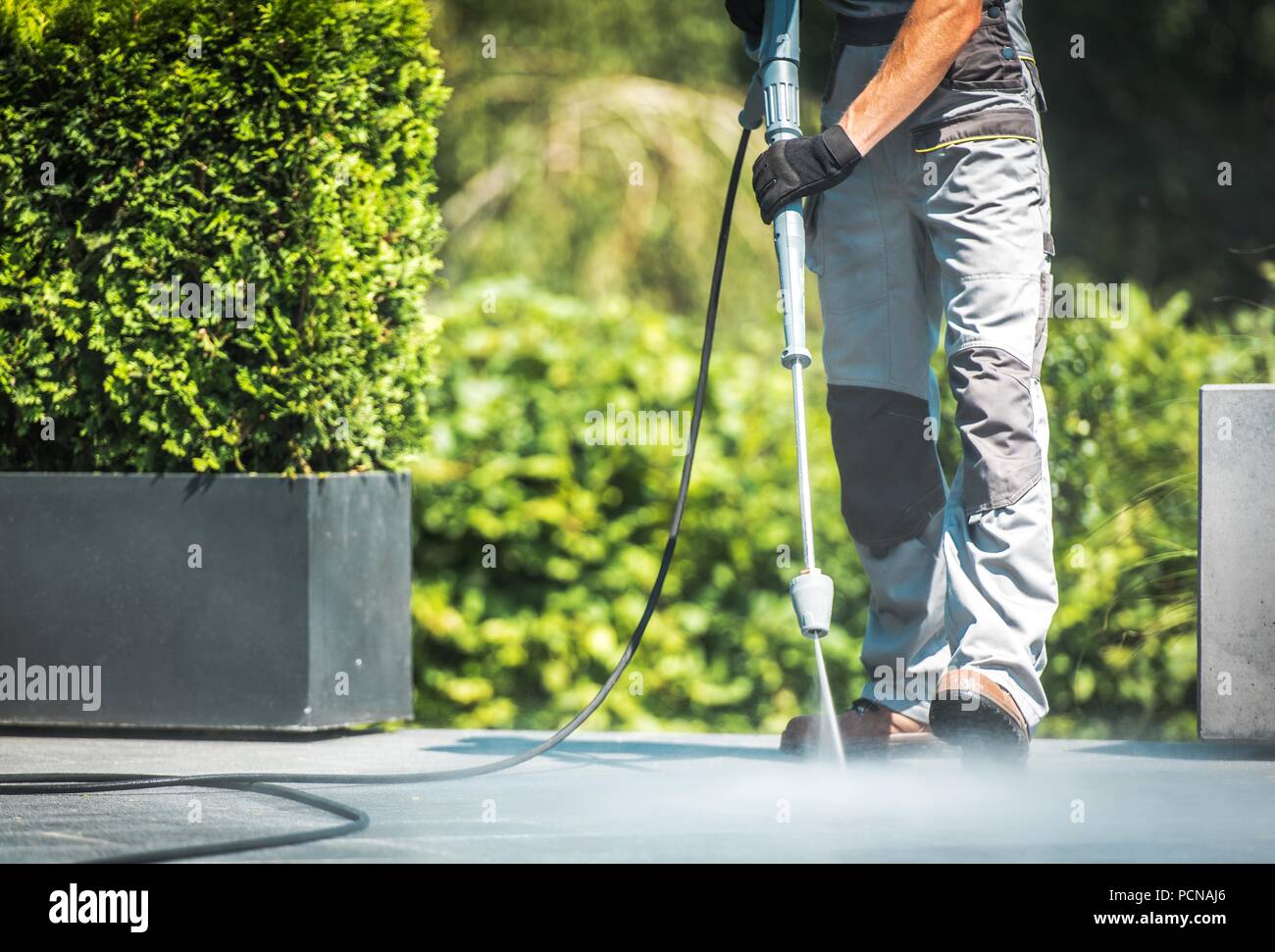 Patio Pressure Cleaning. Caucasian Men Washing His Concrete Floor Patio