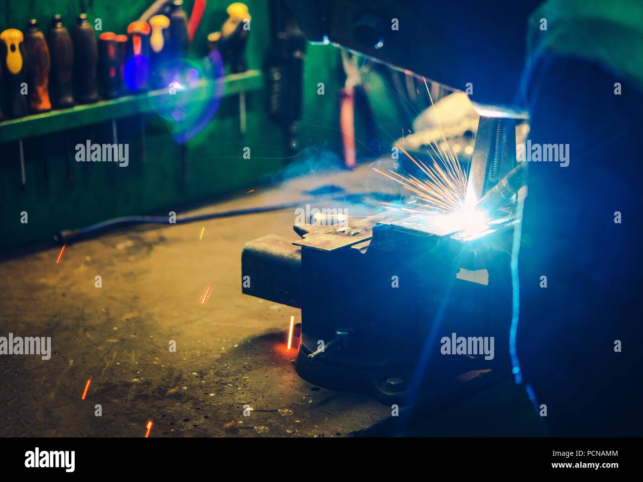 Small Garage Welding Job Closeup Photo. Welder Wearing Eyes and Face