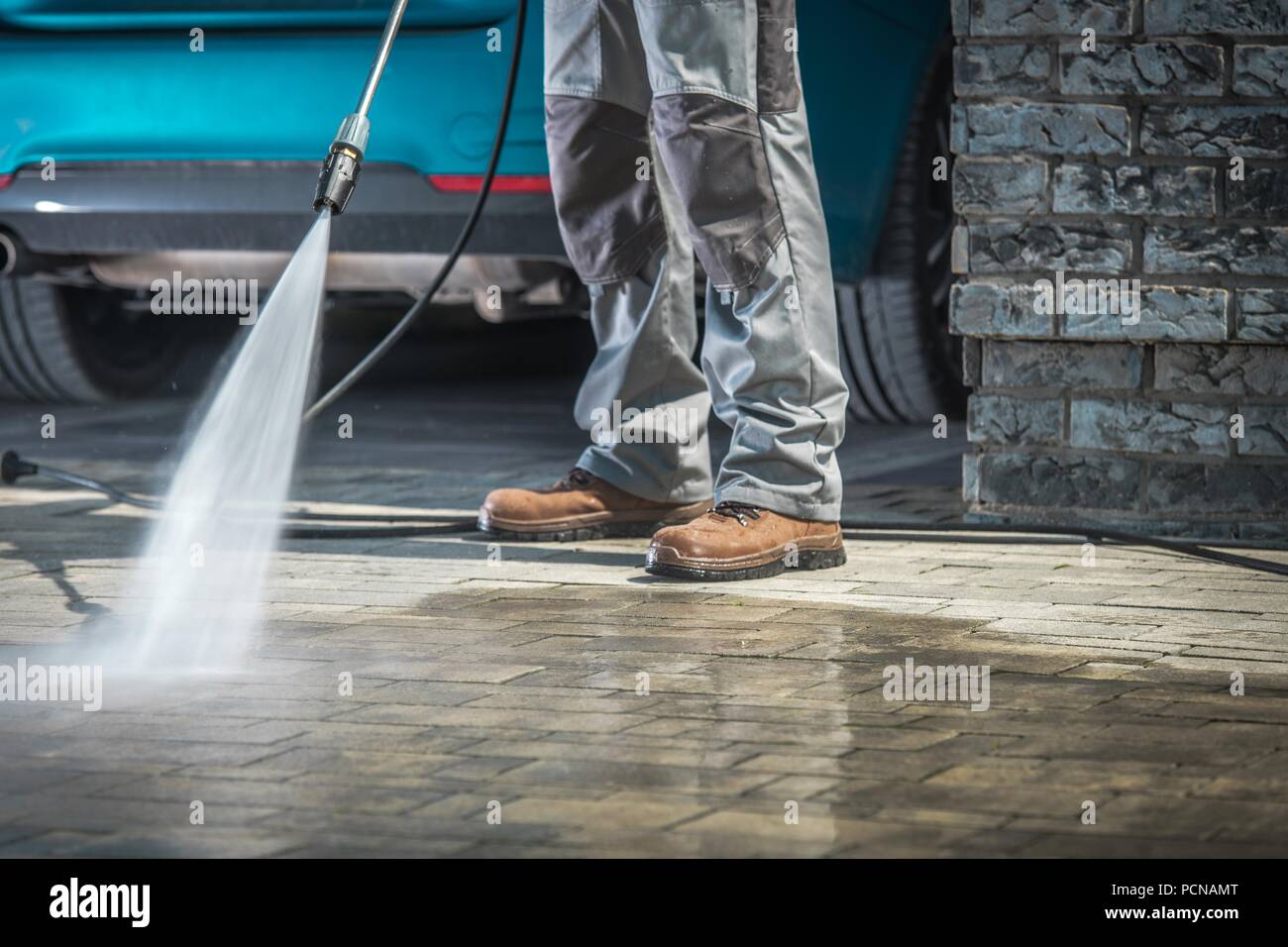 Cobble Stone Driveway Cleaning Using Pressure Washer with Concrete Cleaning Detergent. Closeup Photo. Stock Photo