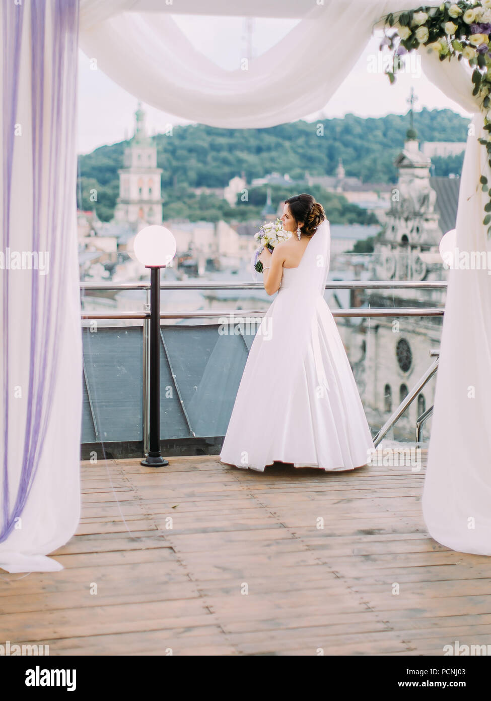 The full-length back view of the bride with the wedding bouquet ...