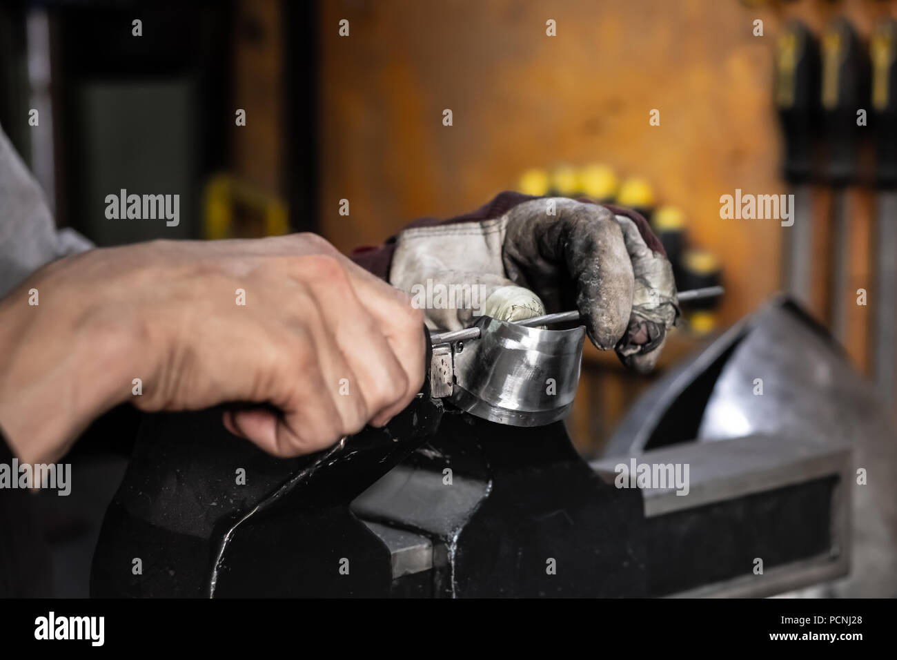 Male metal worker constructing or repairing piece of metal assembly. Man hands working with metal parts in a workshop Stock Photo