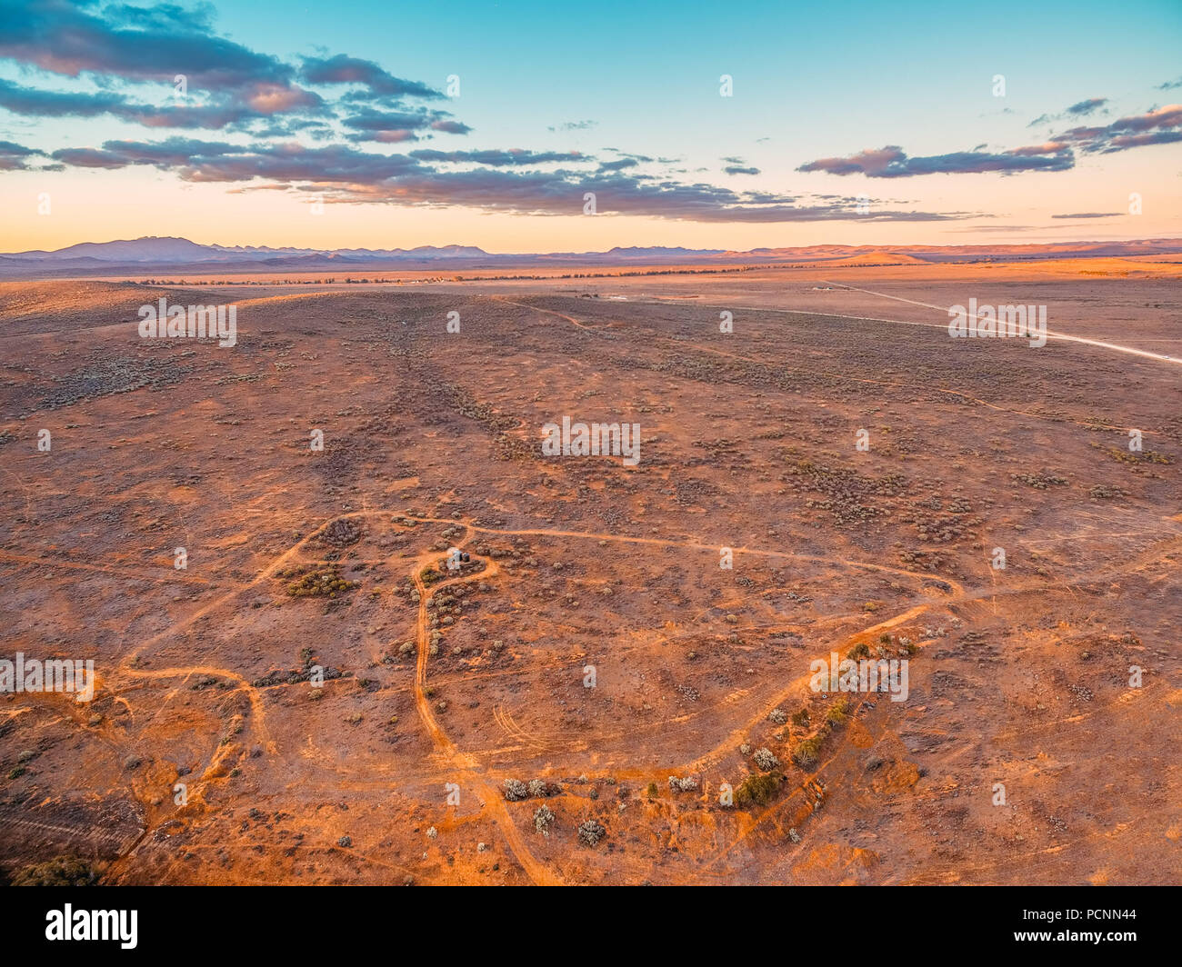 Barren desert land and hills in the distance at beautiful sunset - South Australian aerial landscape Stock Photo