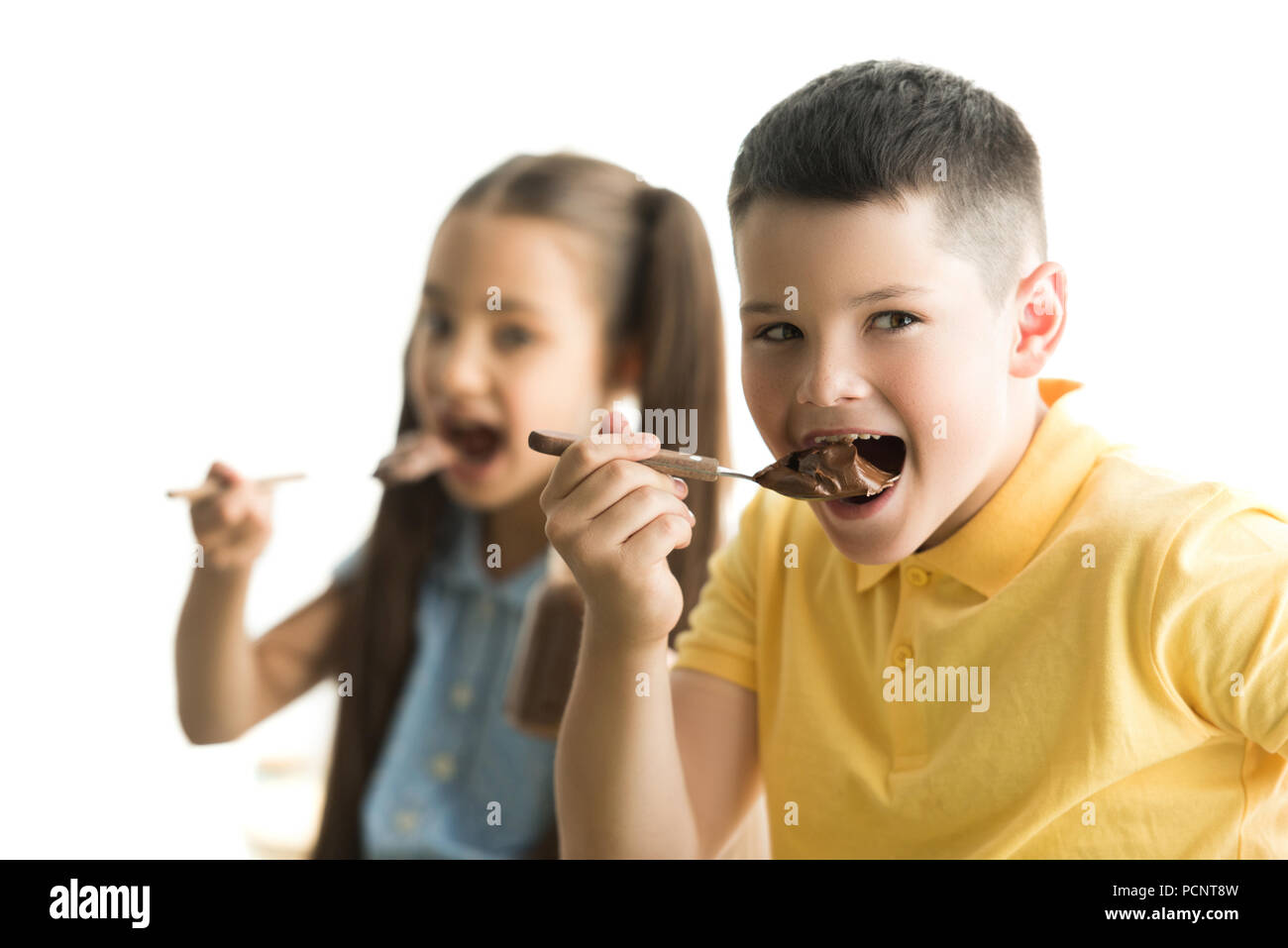 sister and brother eating chocolate in kitchen Stock Photo