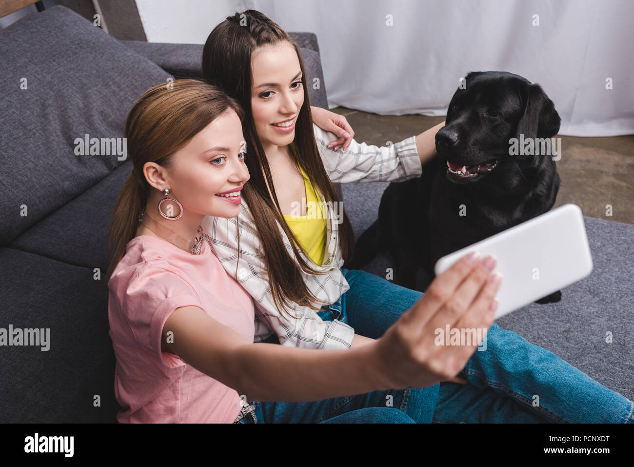 smiling woman taking selfie with female friend and black labrador at ...