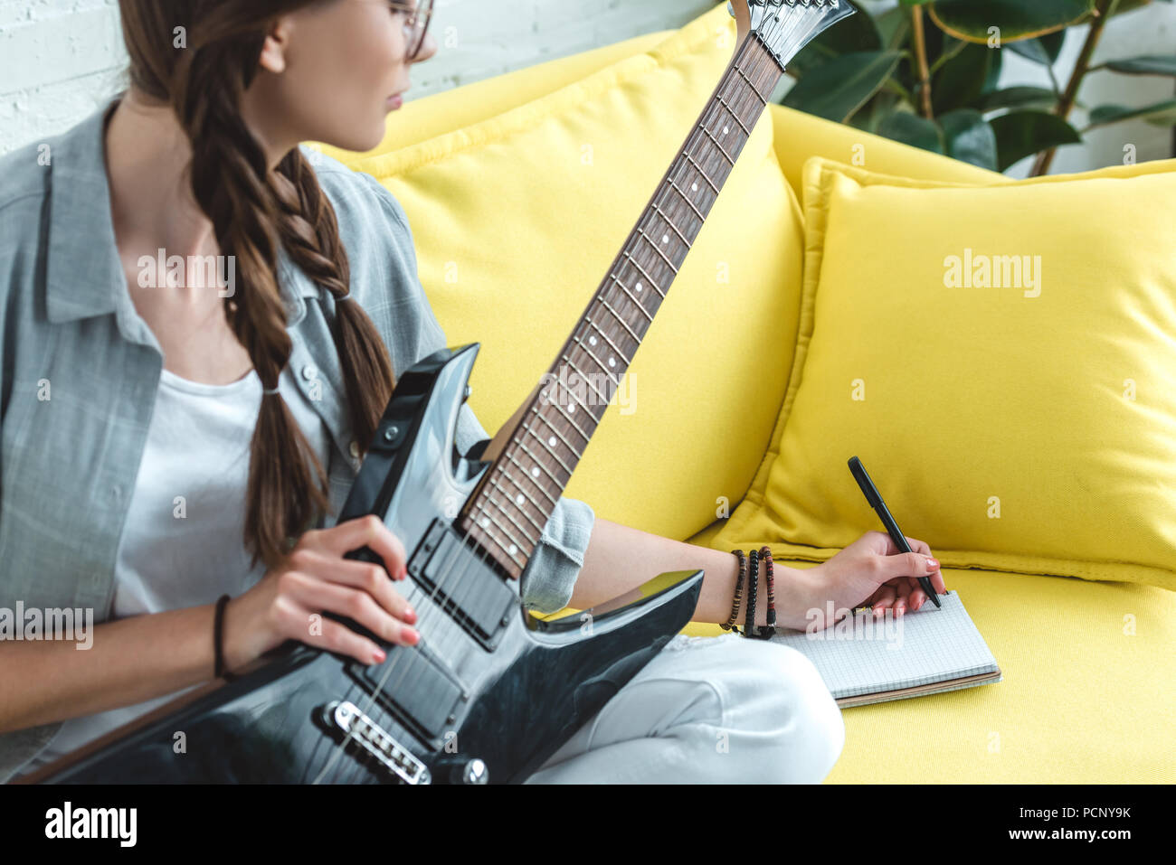 attractive teen girl playing electric guitar and writing song Stock