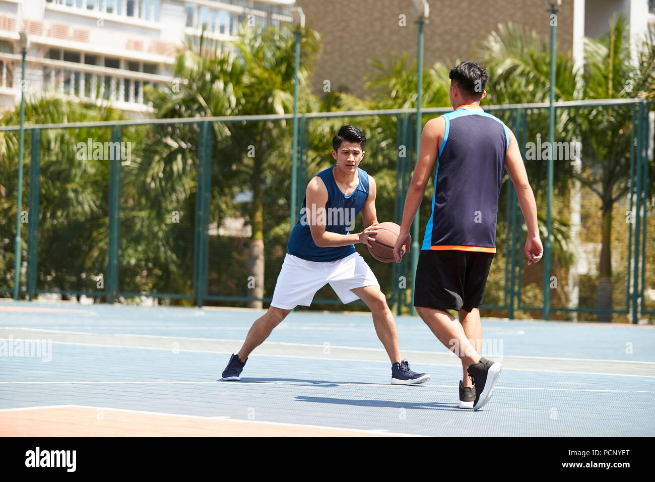 young asian adult players playing basketball on outdoor court. Stock Photo