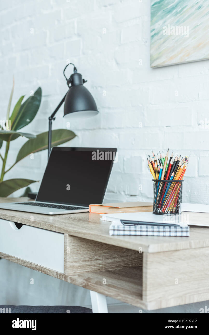 laptop, books, lamp and pencils on table for remote work Stock Photo