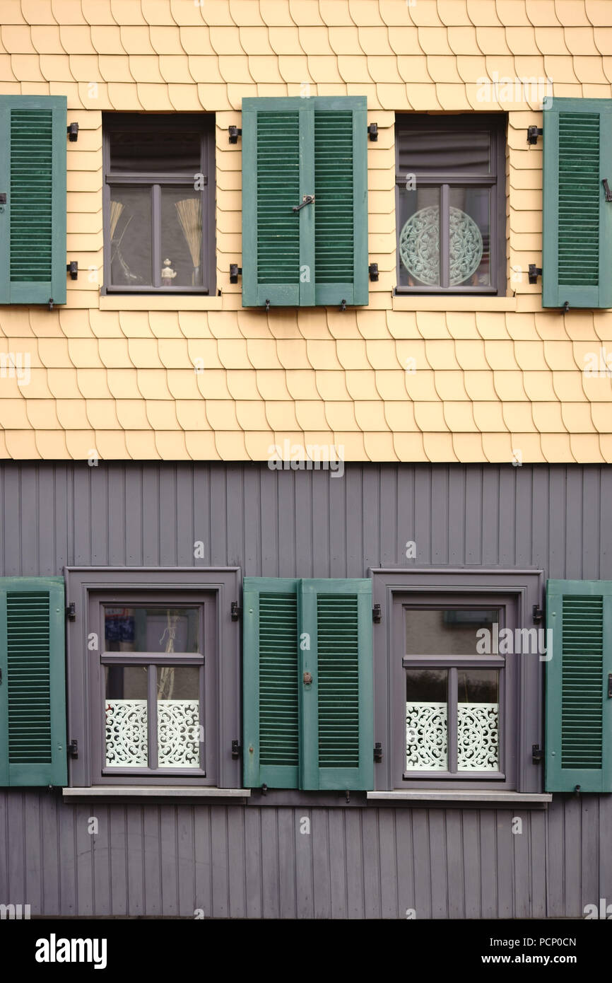 Open shutters on a distinctive facade of yellow shingles. Stock Photo
