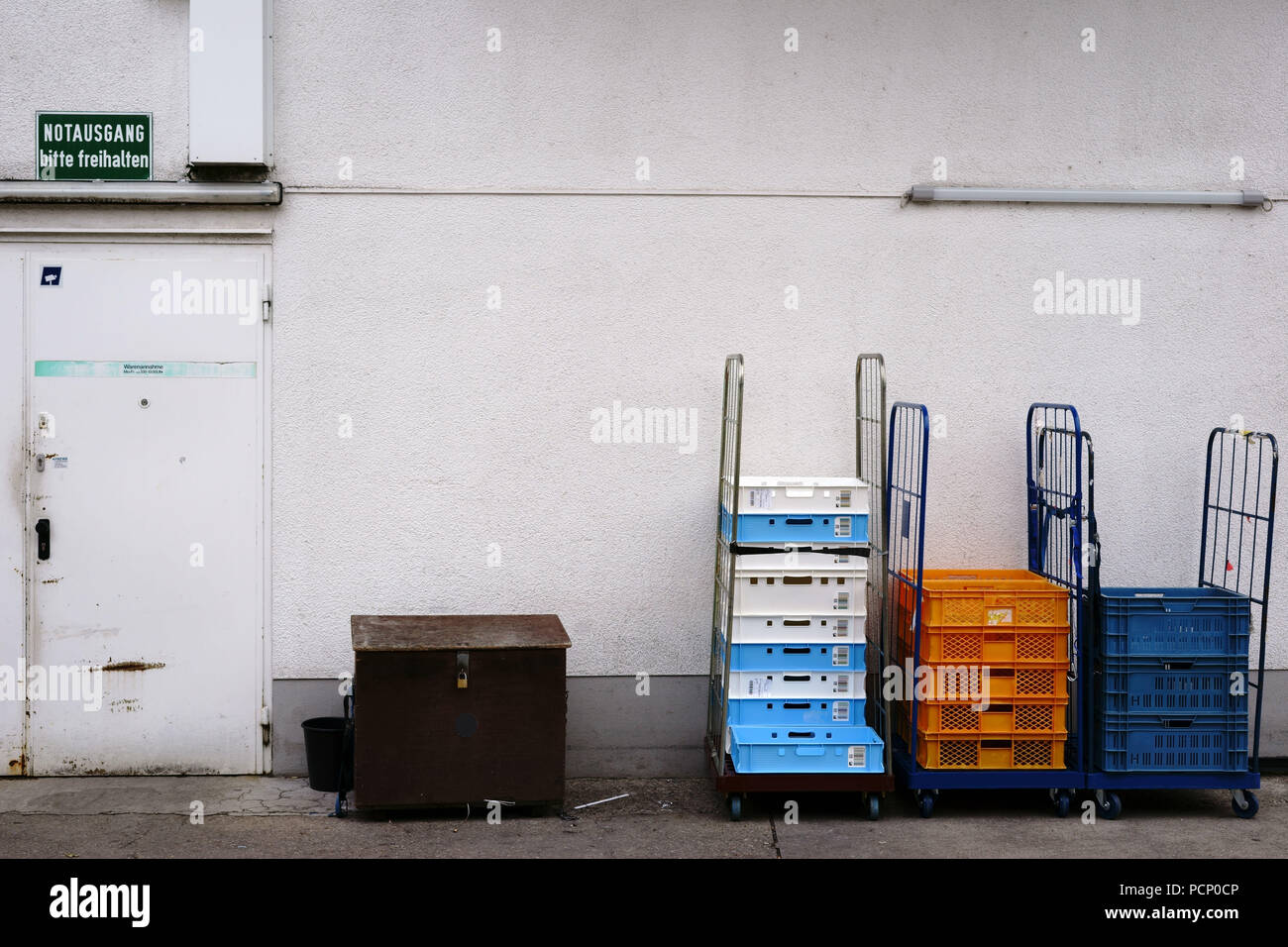 A receiving of goods at the back entrance of a grocery store with boxes and pallets on rollable loading areas. Stock Photo