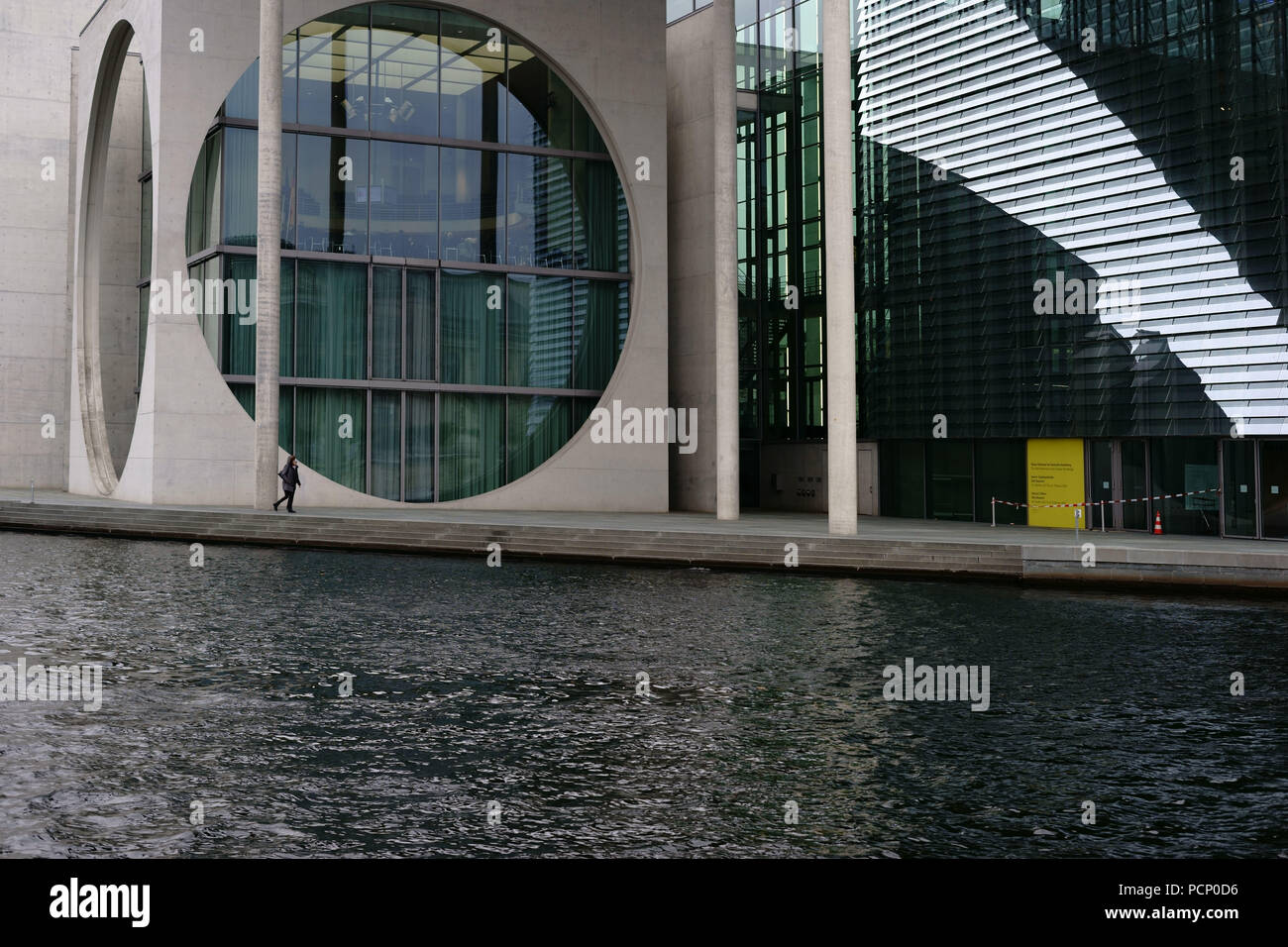 A pedestrian walking along the river Spree pasting the modern architecture of the Marie-Elisabeth-Lüders house in Berlin. Stock Photo