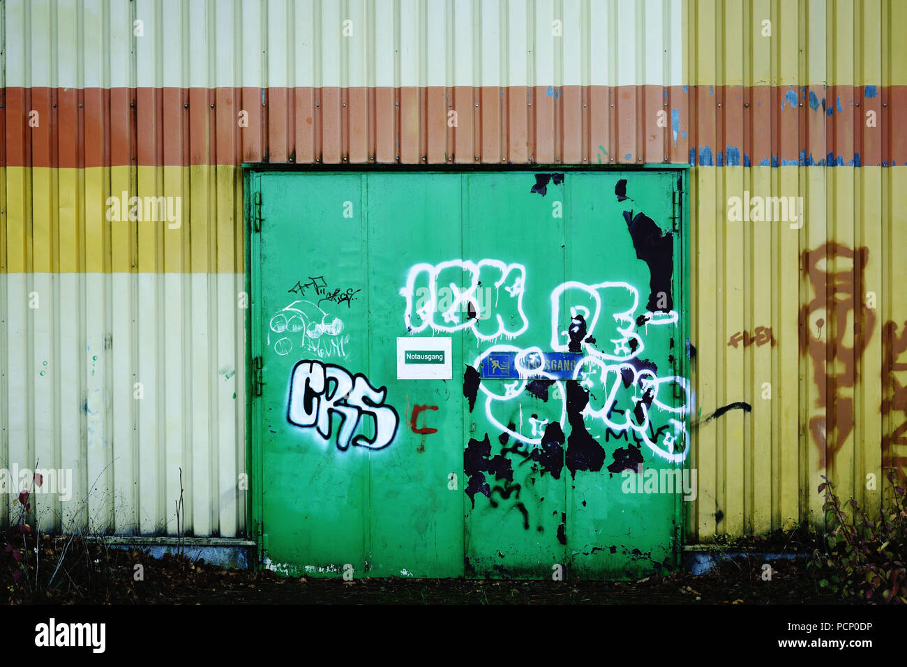A painted steel door with graffiti rather than a fireproof door and emergency exit. Stock Photo