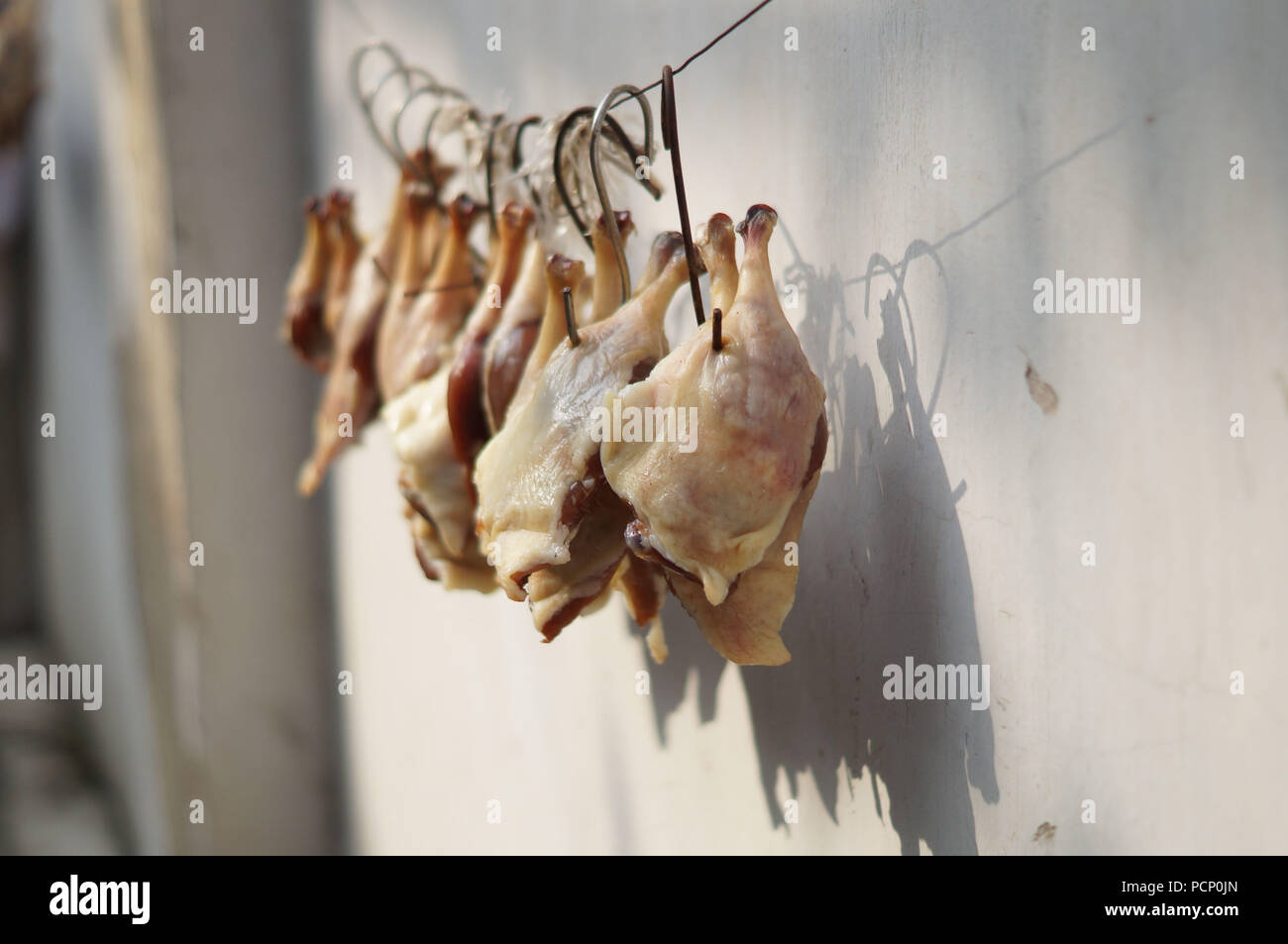 Chicken hanging on hooks to dry outside Stock Photo
