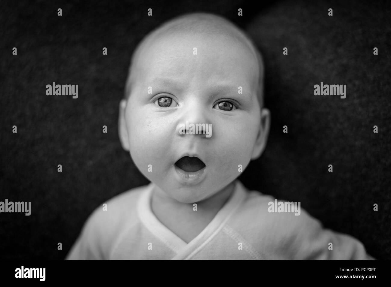 Baby with opened mouth astonished looking, portrait, b/w Stock Photo