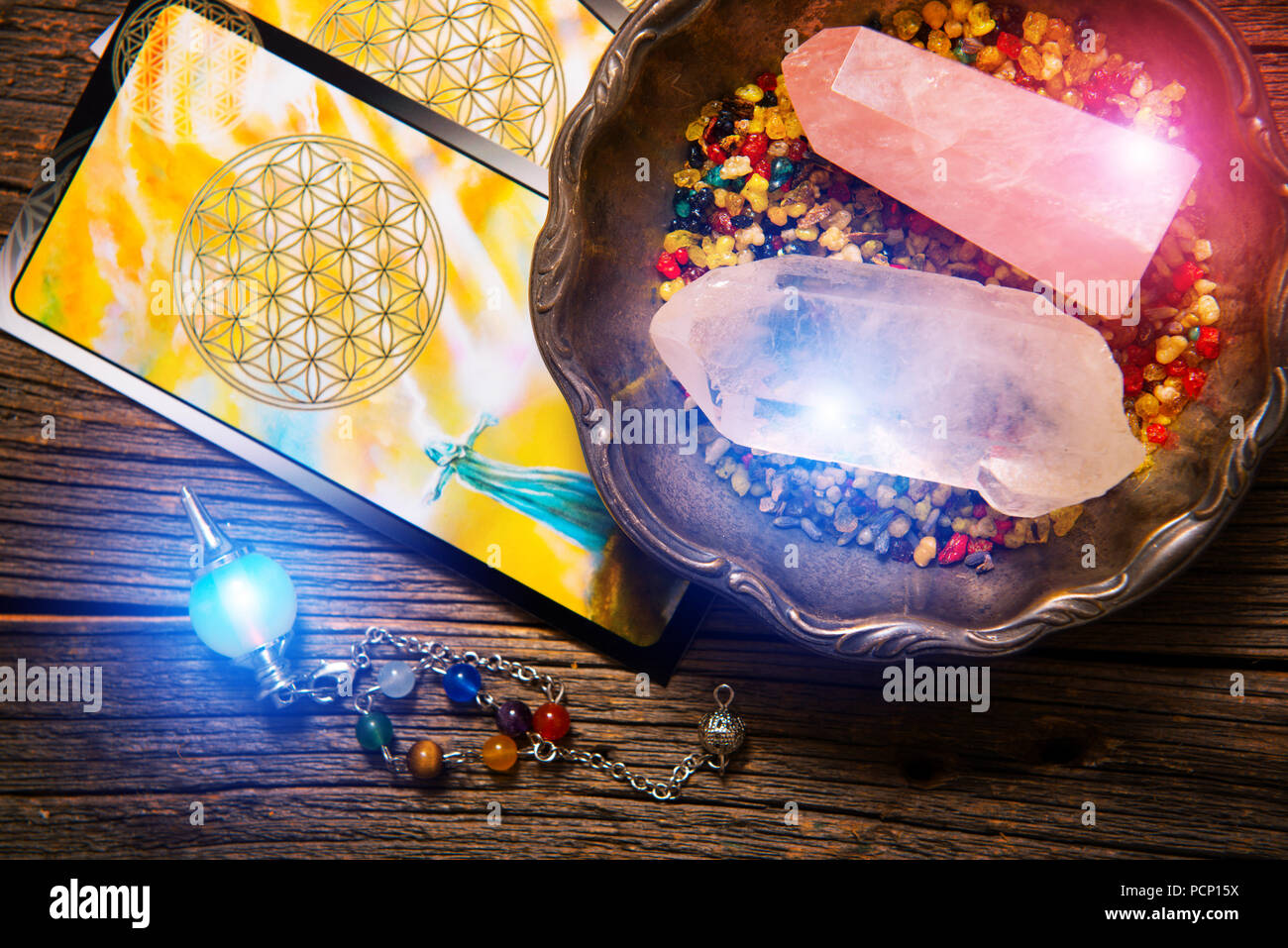 Tarot cards, dowsing tool and crystals on a wooden board Stock Photo