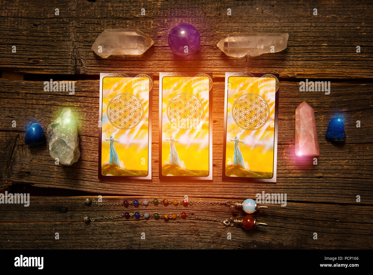 Tarot cards, dowsing tool and crystals on a wooden board Stock Photo