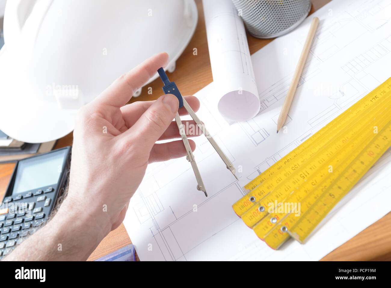 Architect using engineering calculator at his work. Construction plans