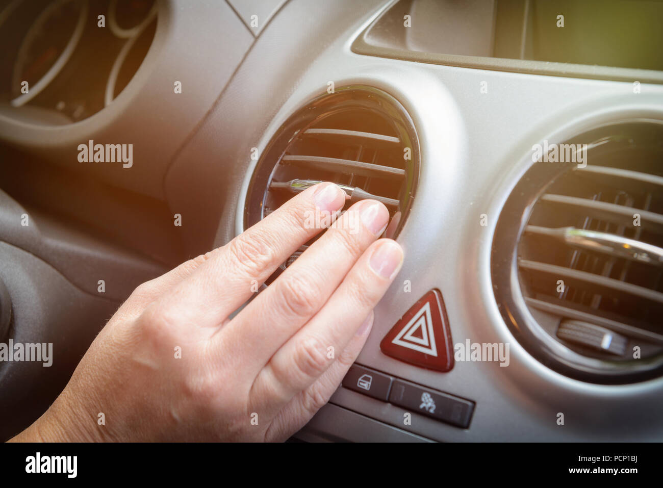 Driver hand tuning air ventilation grille, emergency flasher switch and  light in modern car interior Stock Photo - Alamy