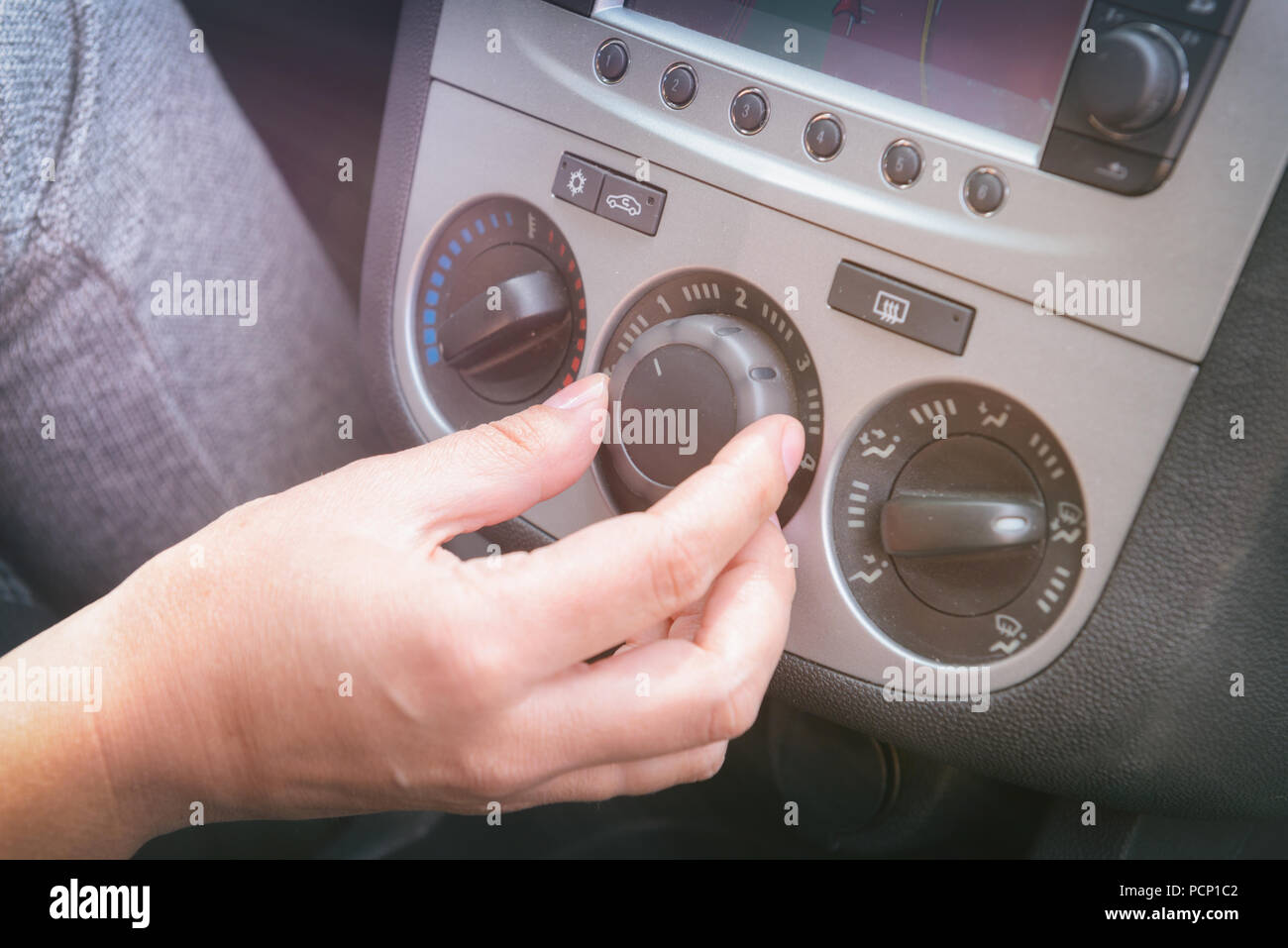 Driver adjusting car airconditioning and ventilation system with fan