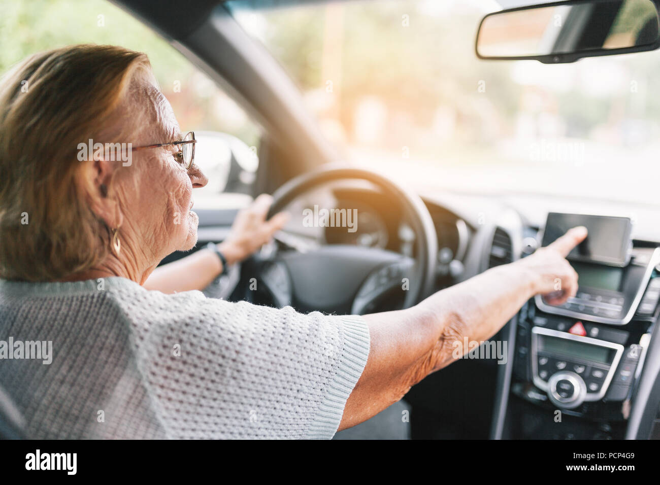 Elderly woman behind the steering wheel of a car using her satnav Stock Photo