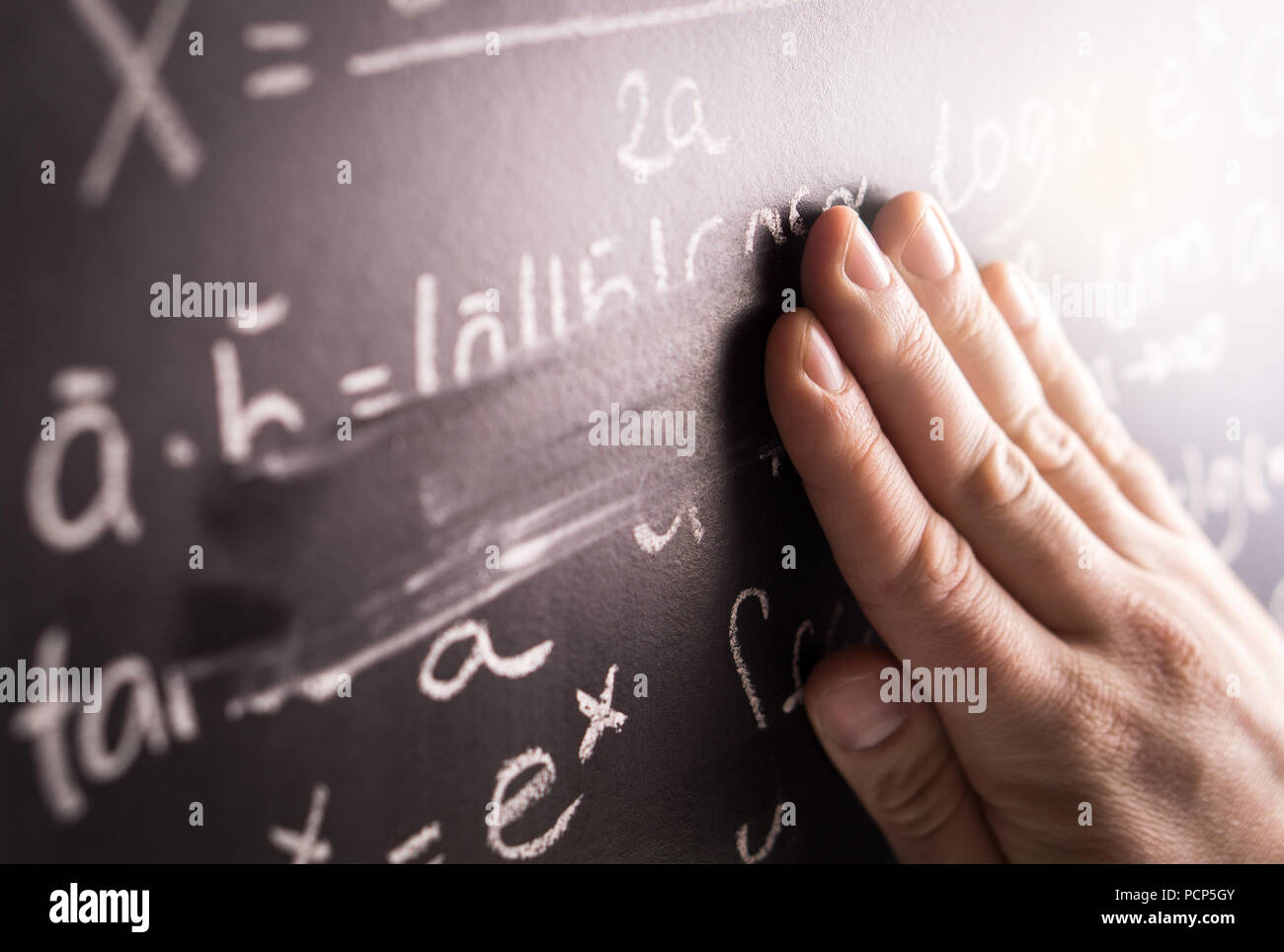 Making mistakes and wrong answer concept. Hand wiping math formula off blackboard in classroom at school. Student or teacher correcting. Stock Photo