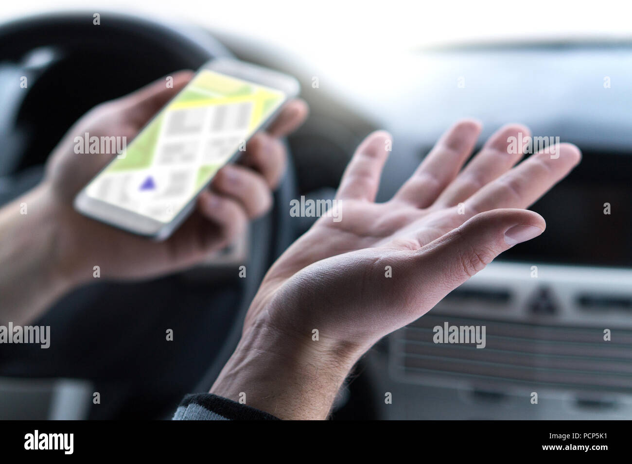 Lost and no GPS connection. Navigation problem. Man using smartphone map application in car. Clueless and confused driver spreading hands. Stock Photo