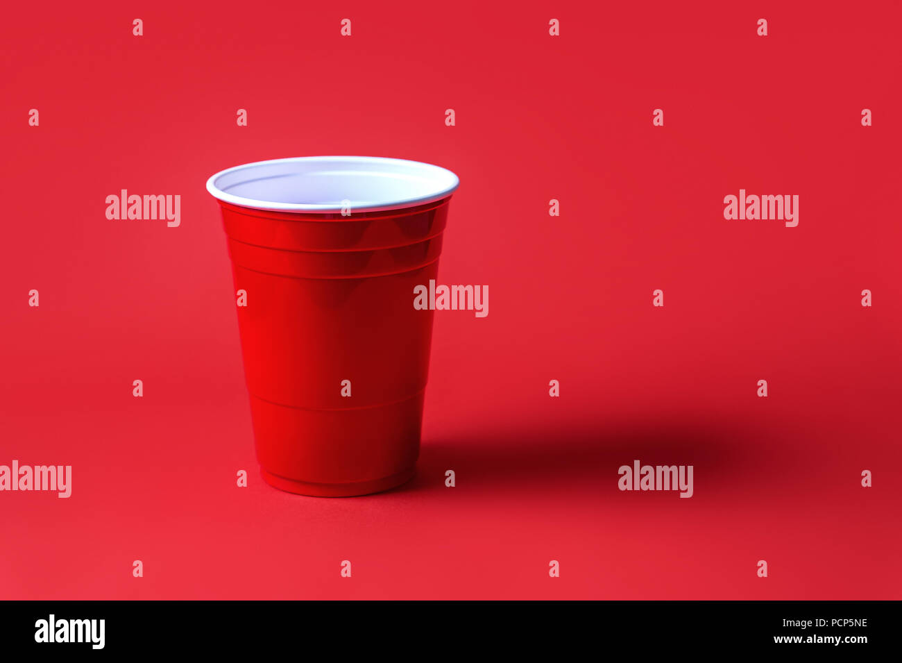 Red party cup on red background. Beer pong tournament or college celebration concept. Stock Photo