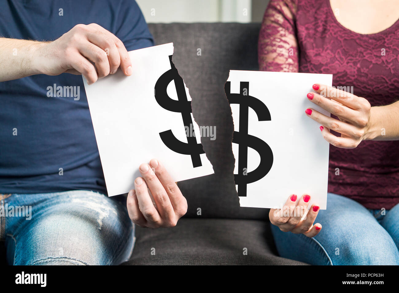 Fight about money or financial argument concept. Man and woman holding ripped paper with dollar sign. Stock Photo