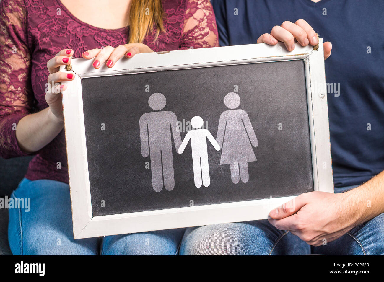 Having children, planning baby, raising kids, adoption, parenthood or infertility concept. Man and woman holding blackboard with family. Stock Photo
