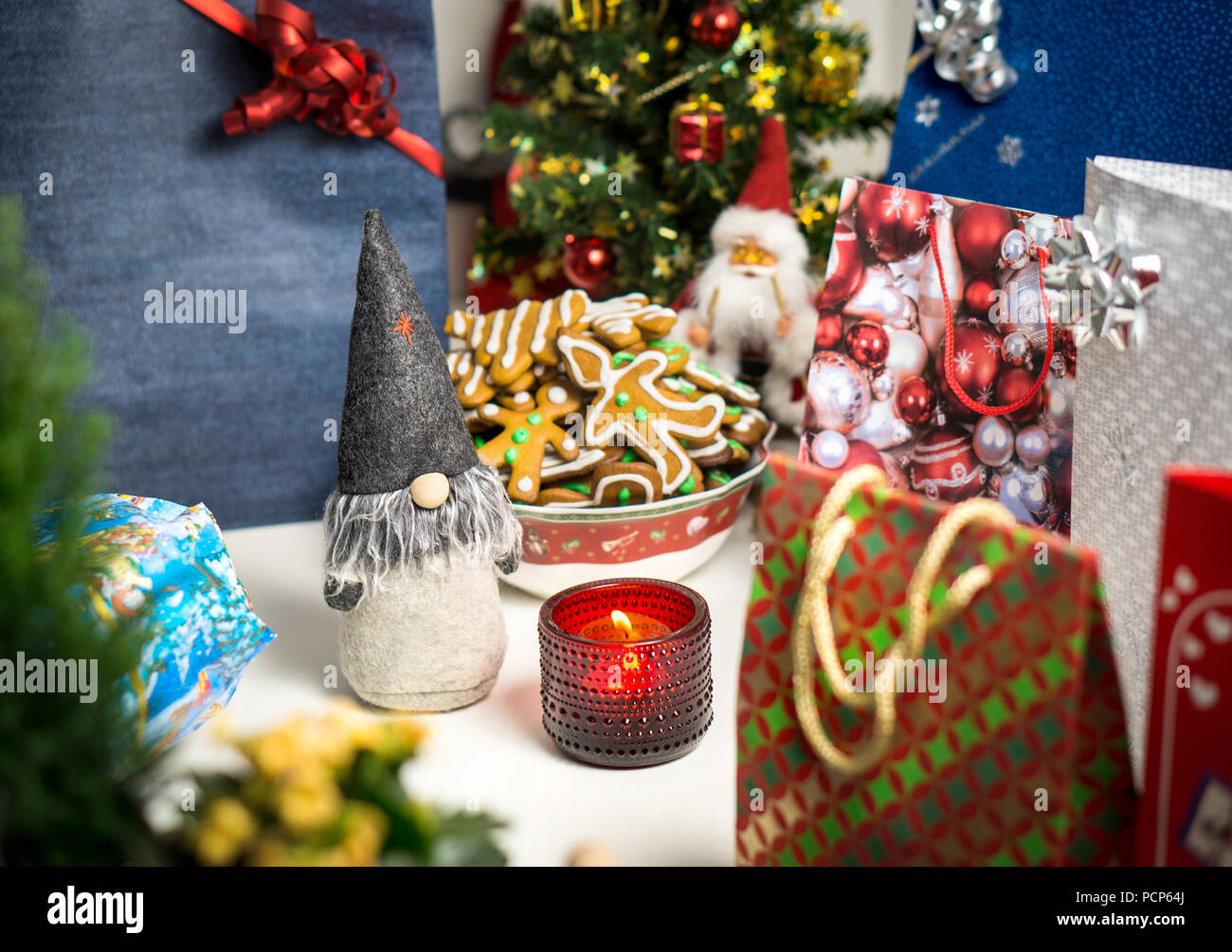 Christmas decorations and presents on table. Little Santa Claus, Christmas tree, candle and gingerbread. Holiday still life layout. Stock Photo