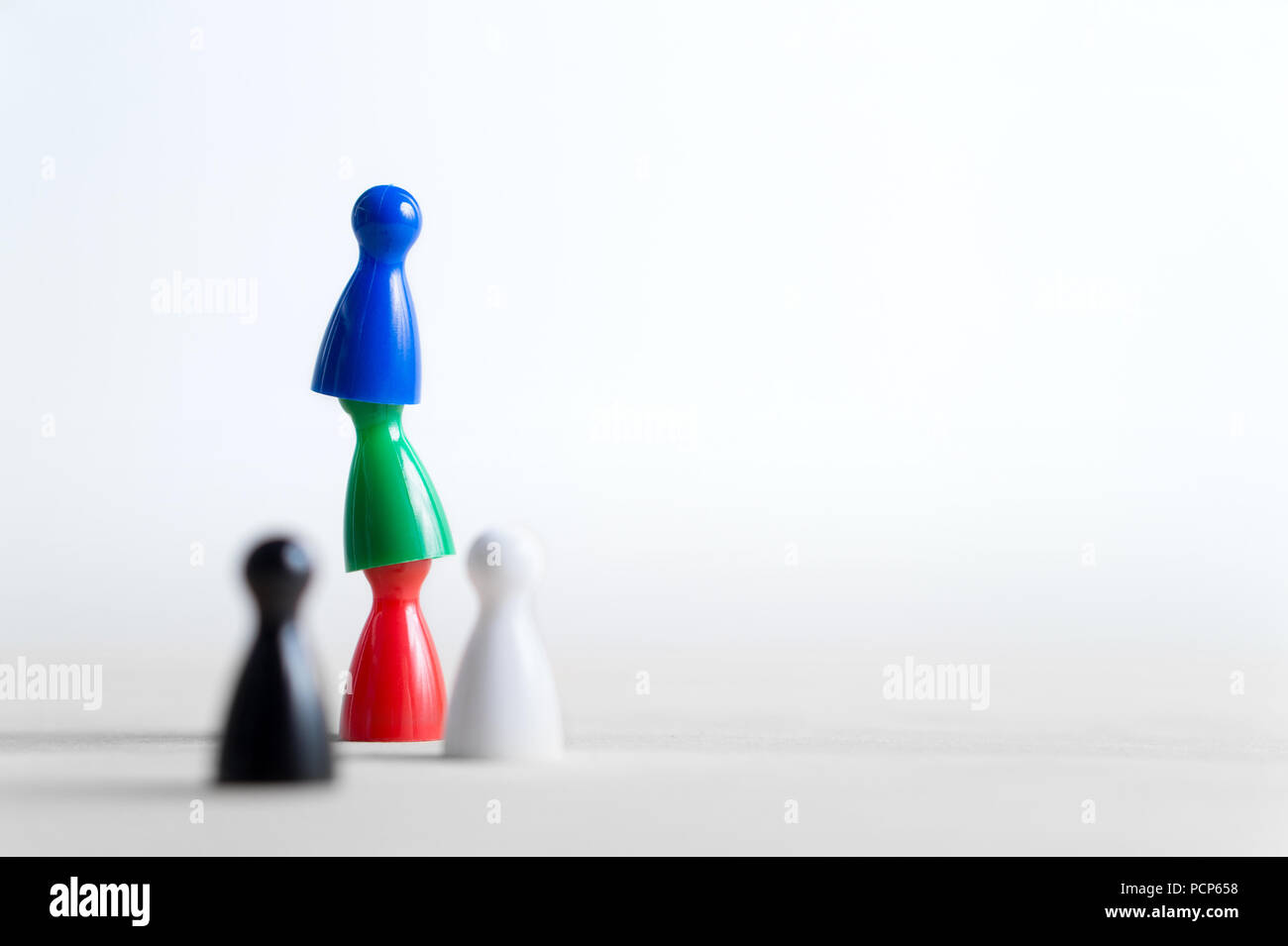 Teamwork, reaching goals, working together and success concept. Cooperation, leadership, achievement and support. Colorful board game pawns. Stock Photo