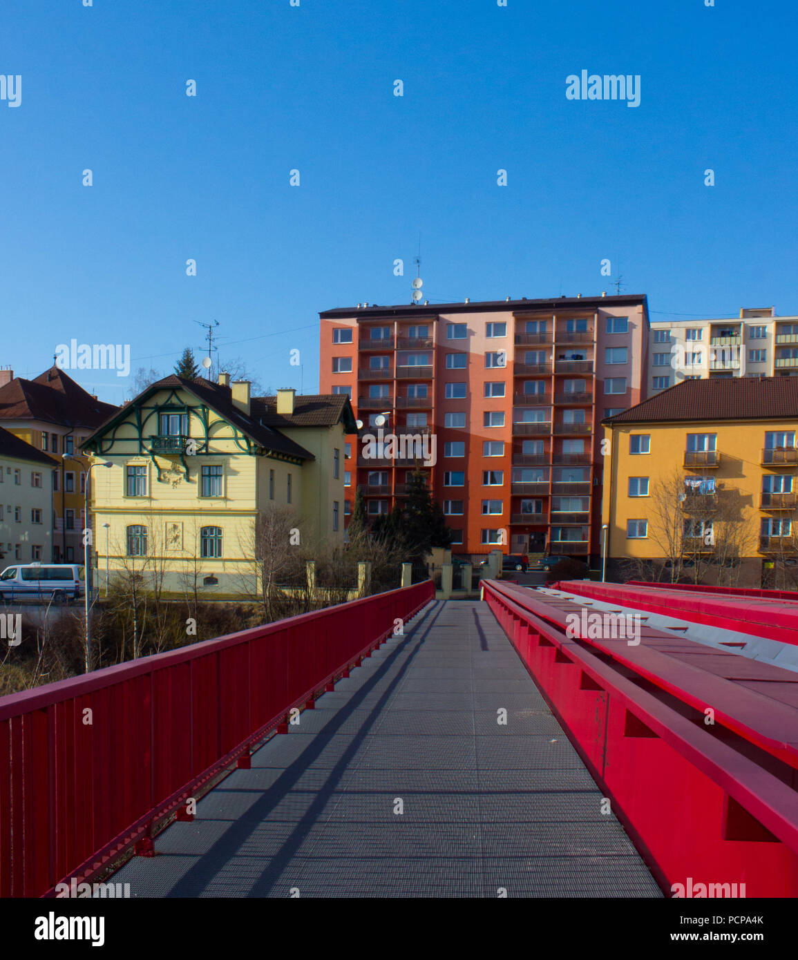 Metallic red bridge over the railway in Frydek Mistek in the Czech Republic. In the background is the colored block of flats. Stock Photo