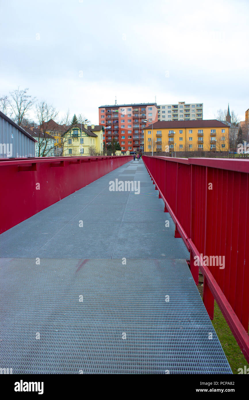 Steel red bridge over the railway in Frydek Mistek in the Czech Republic. In the background are the colored block of flats. Stock Photo