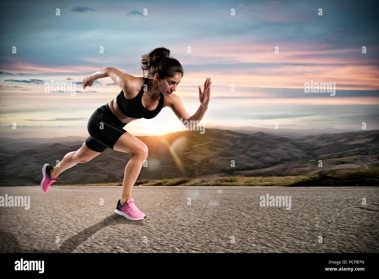 Athletic woman runs on the street during sunset Stock Photo