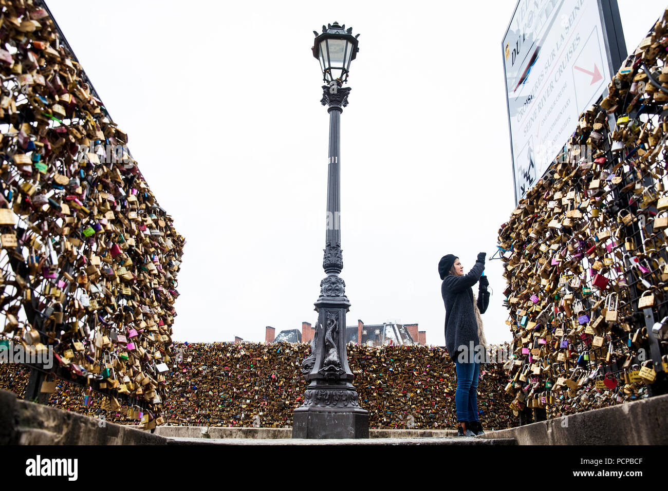 PARIS, FRANCE - MARCH, 2018: Young woman taking a picture of the love locks at Pont Neuf in Paris Stock Photo