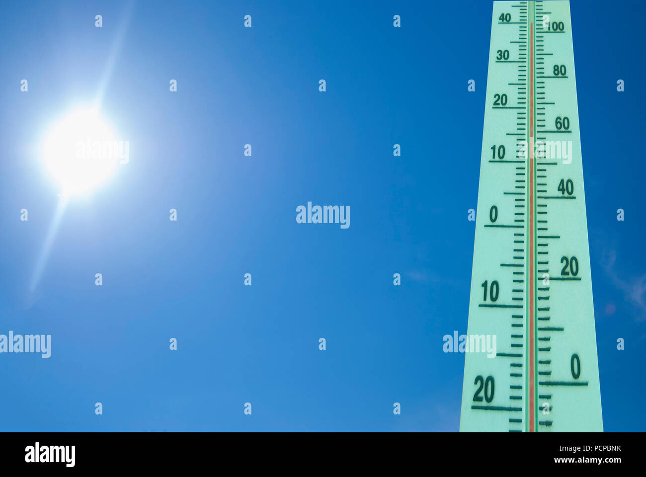 Thermometer with a temperature of +40 degrees Celsius on a background of bright sun and blue sky Stock Photo