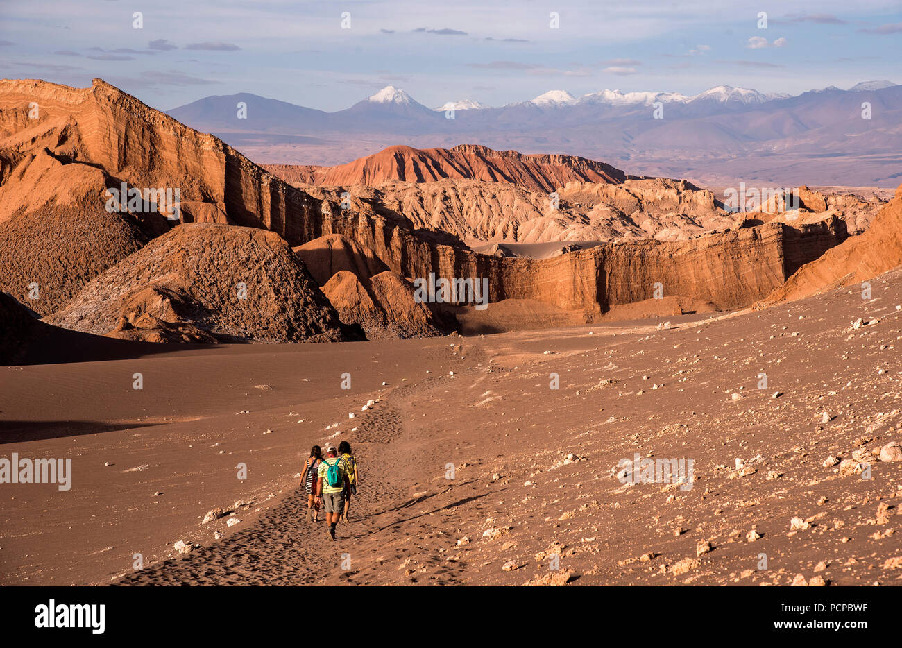Hikers walk towards rock formations in the Atacama Desert, San Pedro, Chile Stock Photo