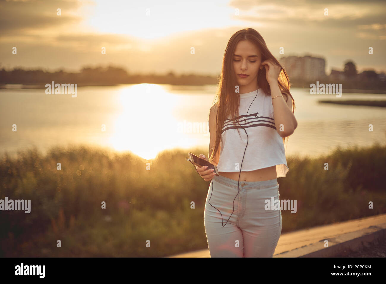 Young beautiful caucasian girl listening to music with smartphone walking in the city with headphones smiling - relax, youth, emancipation concept Stock Photo