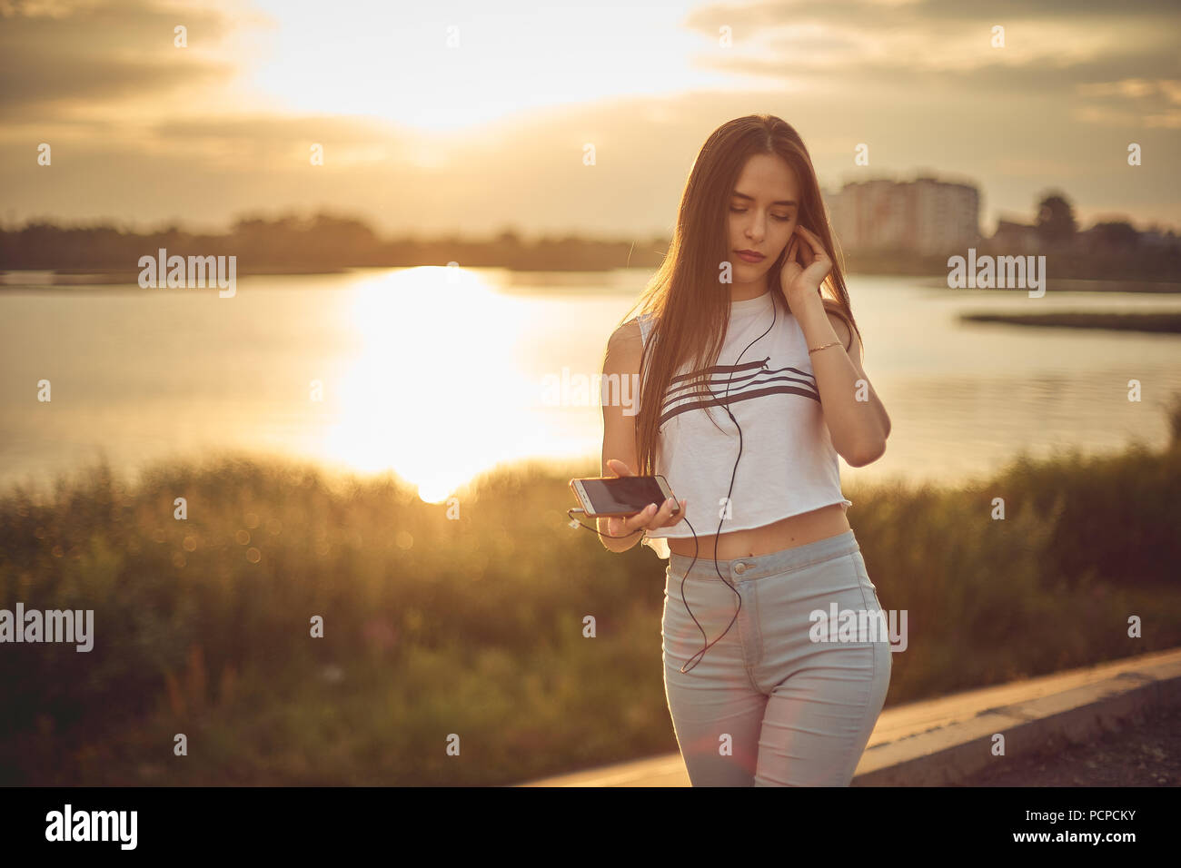 Young beautiful caucasian girl listening to music with smartphone walking in the city with headphones smiling - relax, youth, emancipation concept Stock Photo